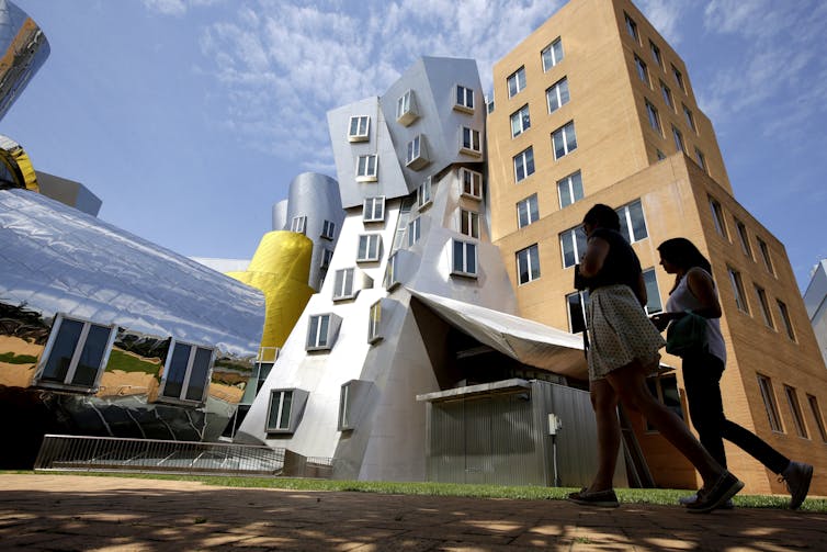 Young people walk past a modern building.