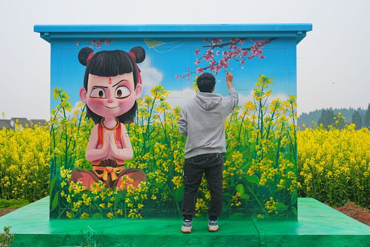 A man stands next to a large painting of an animated character
