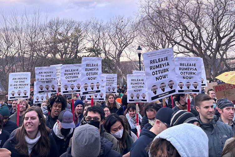 A crowd of protesters outside holding signs.