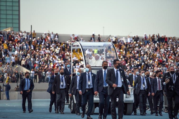 Pope Francis greeting a sports stadium full of people in Iraq.