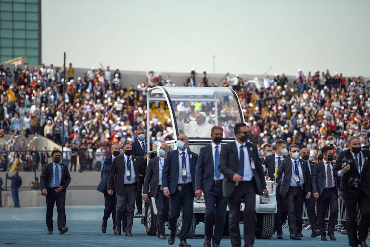 Pope Francis greeting a sports stadium full of people in Iraq.