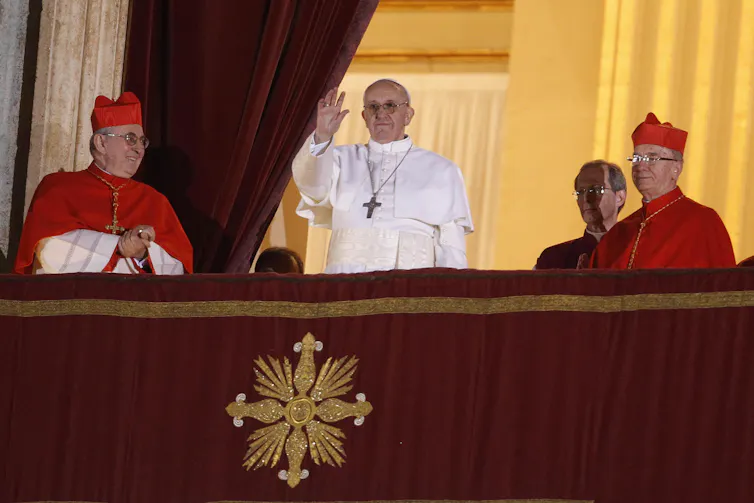 Pope Francis greets a crowd from the balcony of Saint Peter's Basilica.