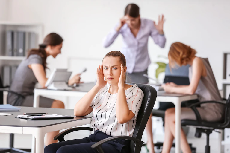 Employée se bouchant les oreilles à son bureau à cause du bruit
