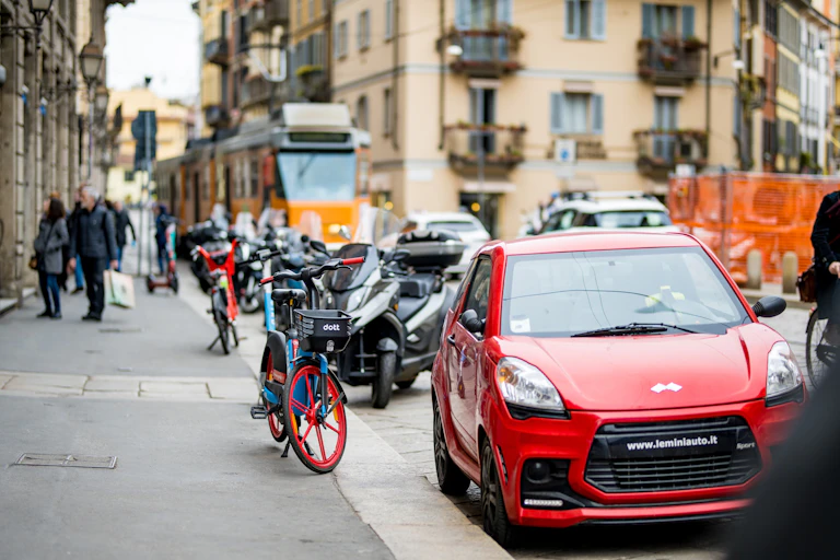 Coches, bicicletas eléctricas y un tranvía en una calle.