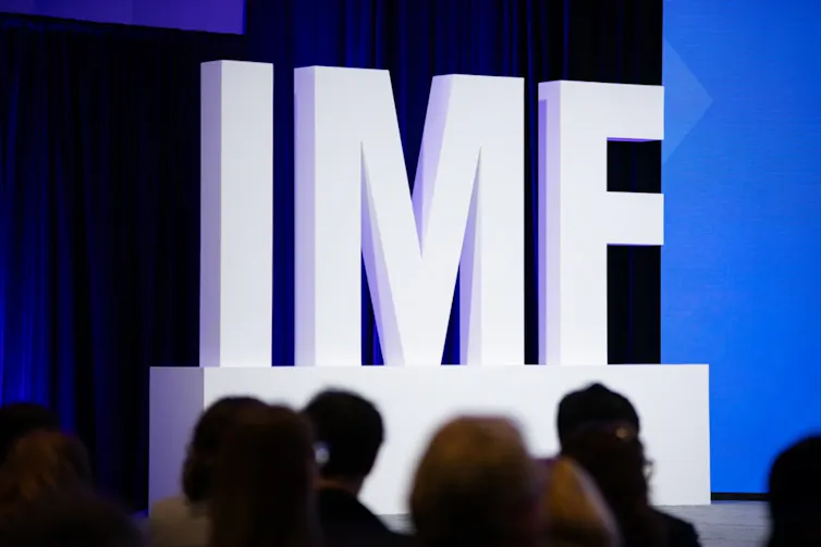 delegates at the imf spring meeting in washington seated in front of large IMF branding