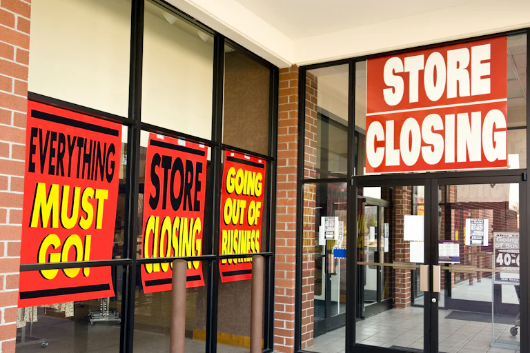 exterior shot of a shop with closing down sale signs on it.