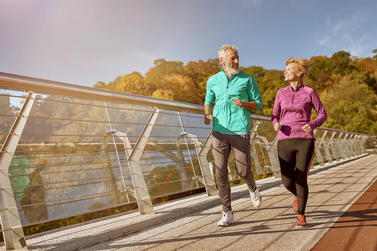 An older couple go for a run together outdoors.