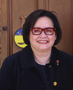 A woman smiling wearing glasses.
