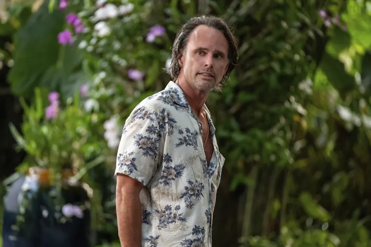 El hombre de la camisa hawaiana con una cara brillante.