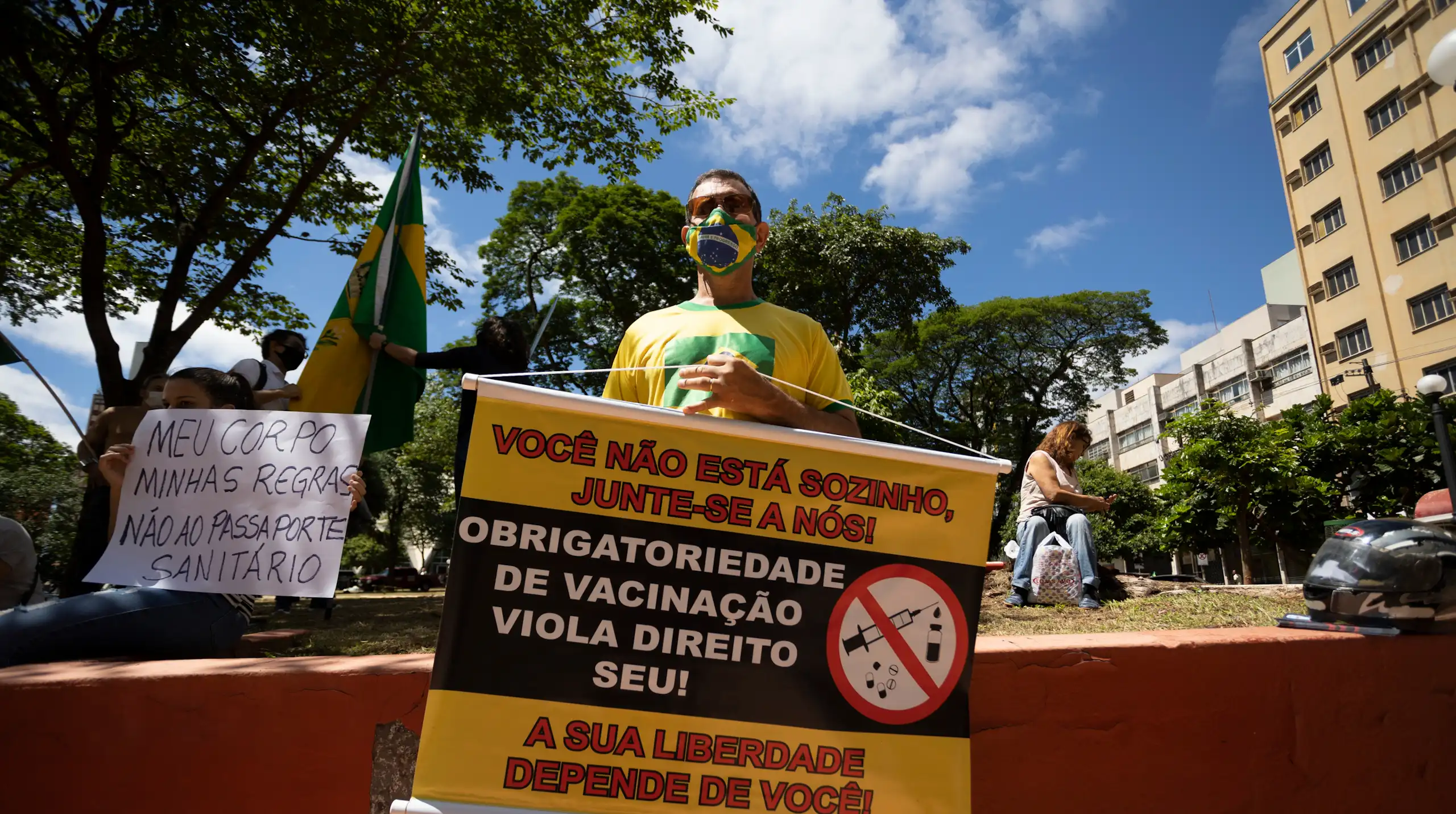 Two protestors holding anti-vaccination signs in Brazil.