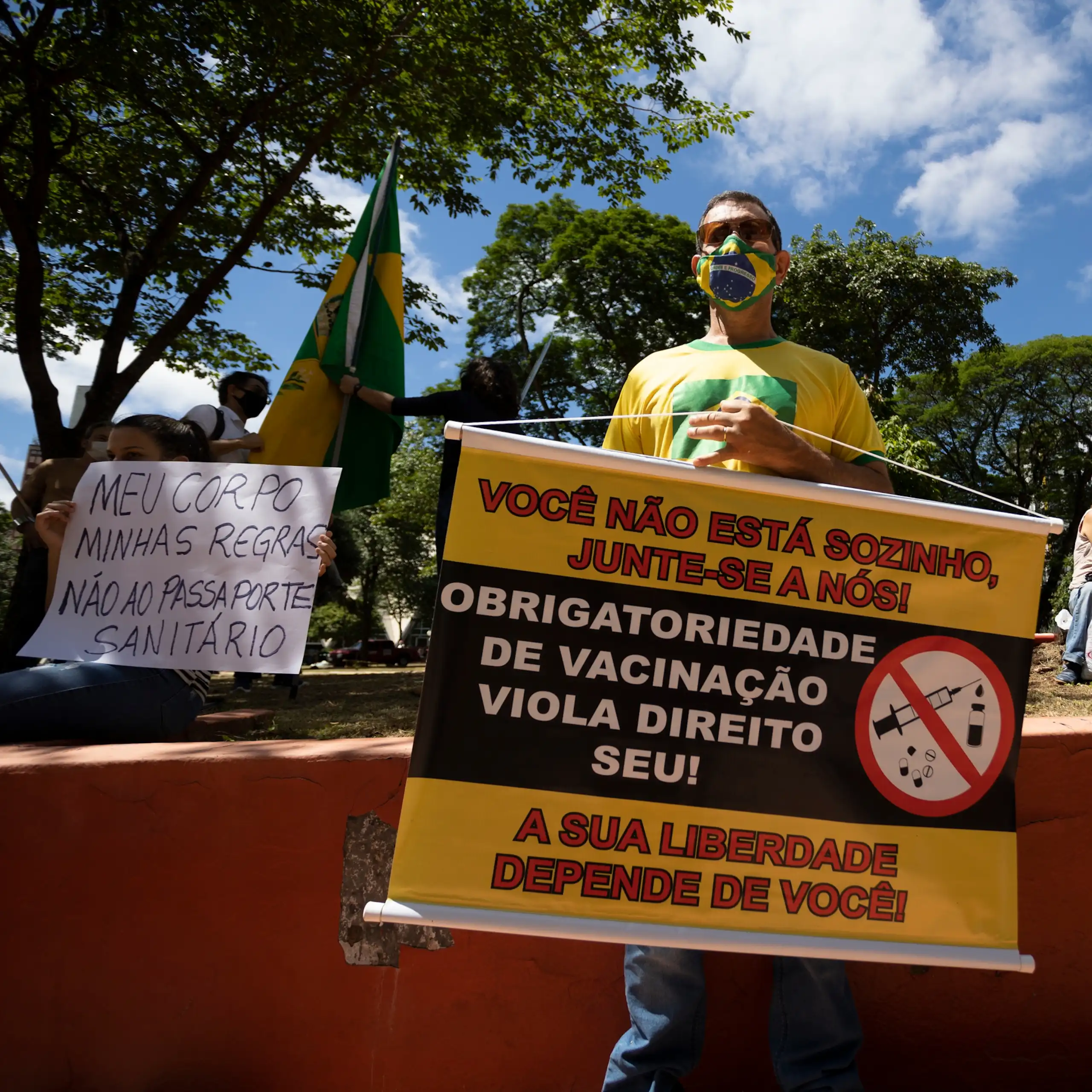 Two protestors holding anti-vaccination signs in Brazil.