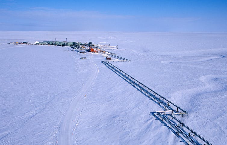 A group of buildings and pipes sit atop a snow-covered landscape.