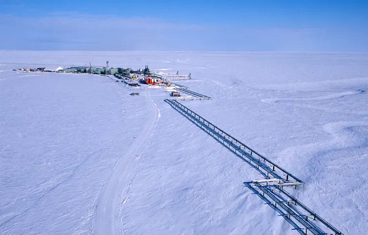 A group of buildings and pipes sit atop a snow-covered landscape.
