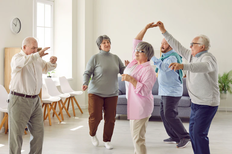 Un groupe de personnes âgées exécutent des mouvements de danse dans un salon.