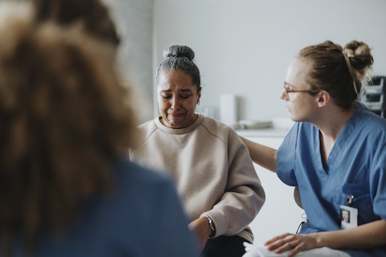 Patient crying while a health care worker consoles them
