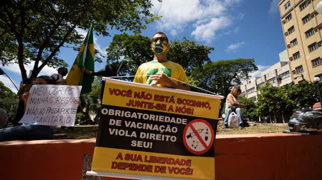Manifestante segurando cartaz contra a vacinação no Brasil.