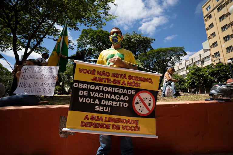 Manifestante segurando cartaz contra a vacinação no Brasil.