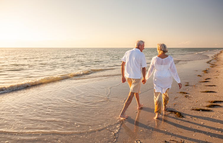 Happy senior man and woman old retired couple on the beach