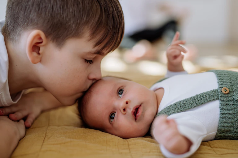 A boy kissing a little baby.