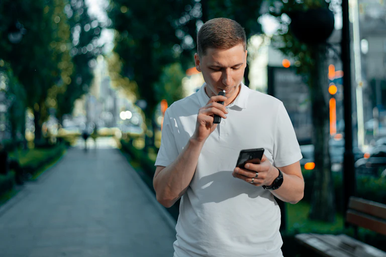 A young man vaping in the street.