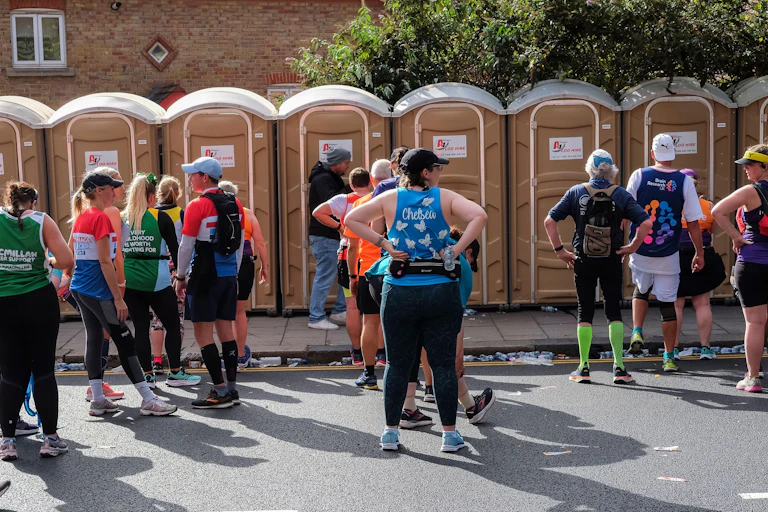 A group of marathon runners queue outside of the port-o-loos.