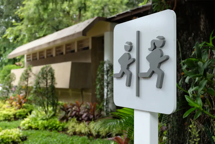 A bathroom sign depicting a male and female stick figure running.