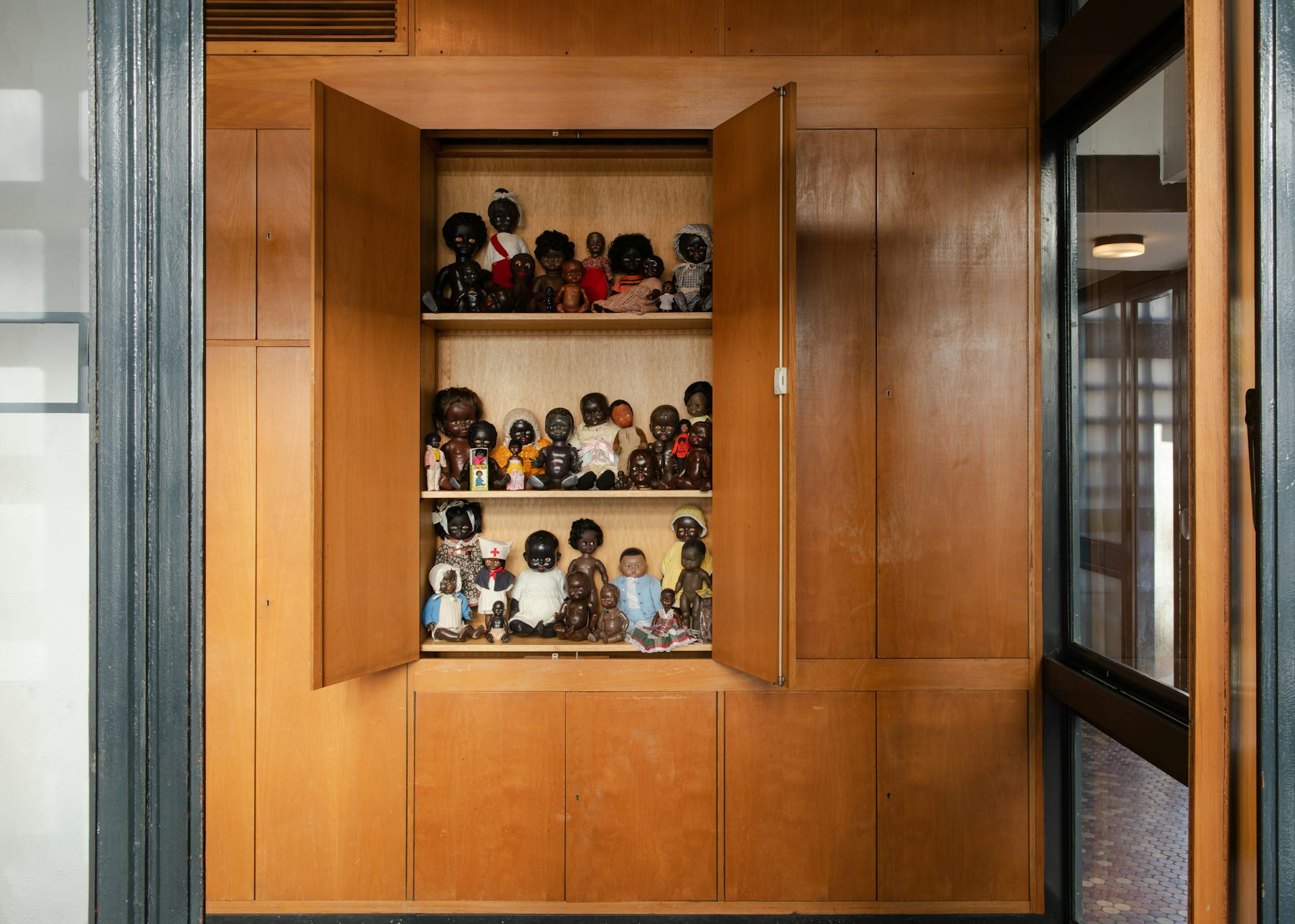 A photo of a cupboard with black dolls on it.