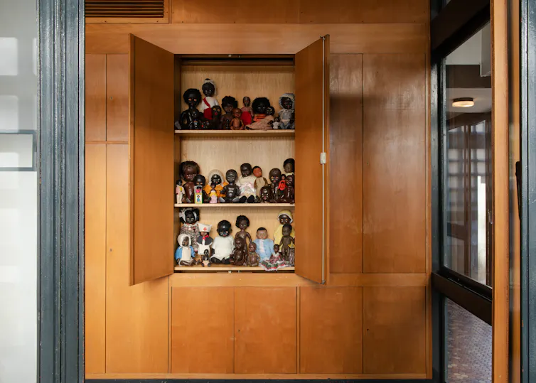 A photo of a cupboard with black dolls on it.