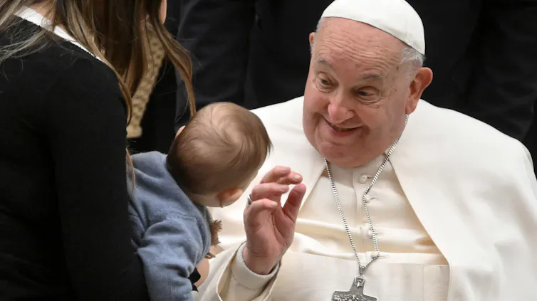 Pope Francis makes a smiley face at a toddler.