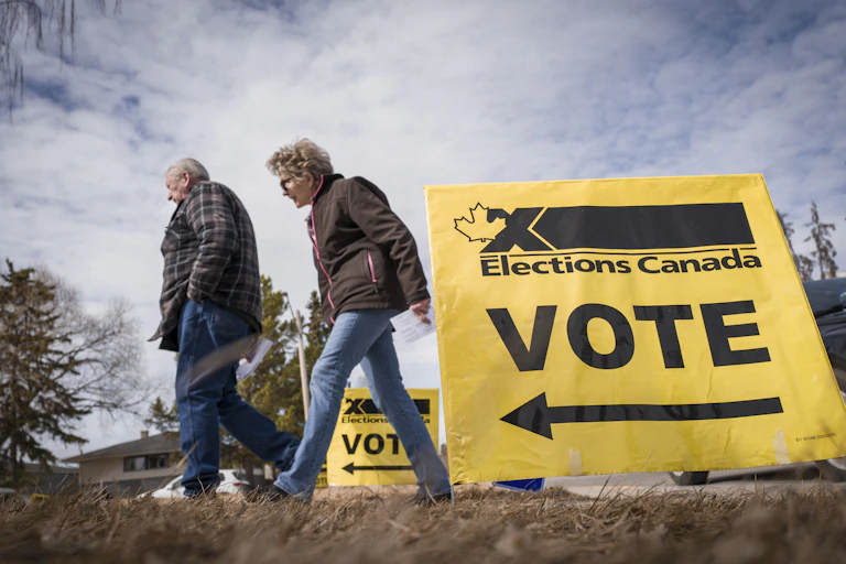 Two people walking between yellow signs reading Elections Canada Vote