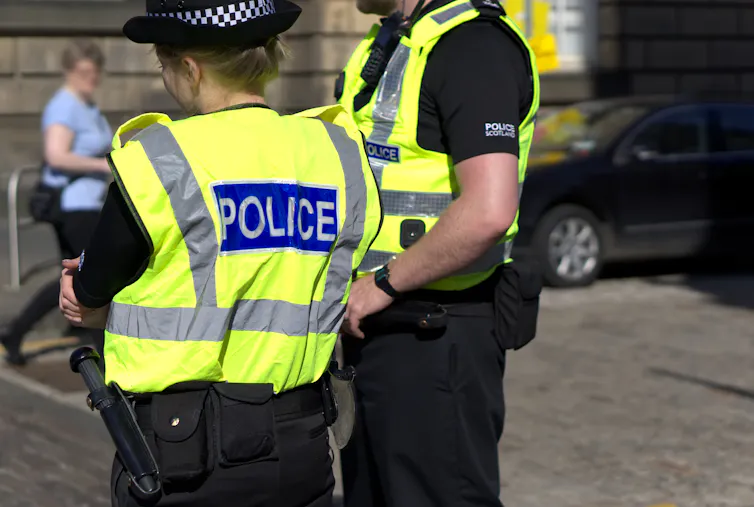 two police officers on duty in hi-vis vests and police scotland shirts