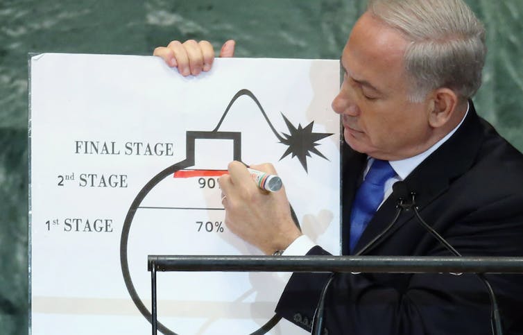 A man draws a red line on a cartoon bomb.