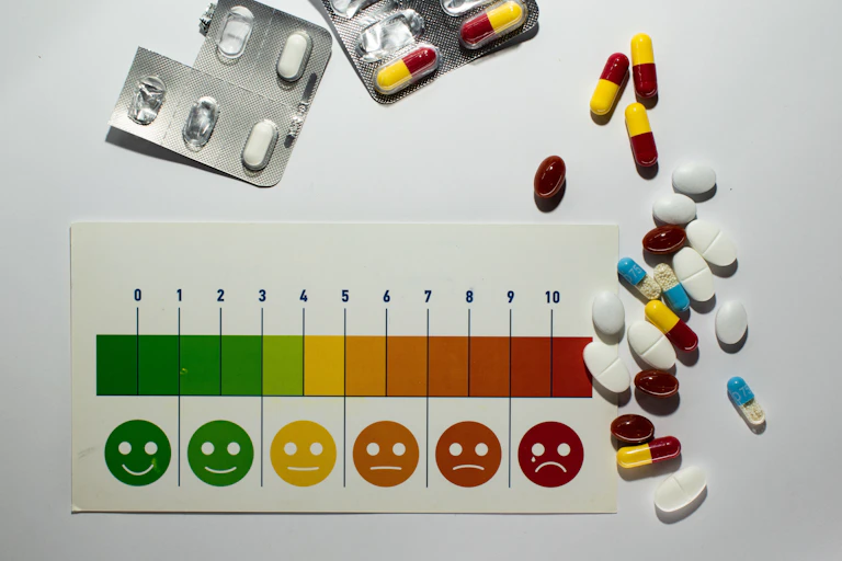 A pain rating scale surrounded by pills and blister packs of pills.