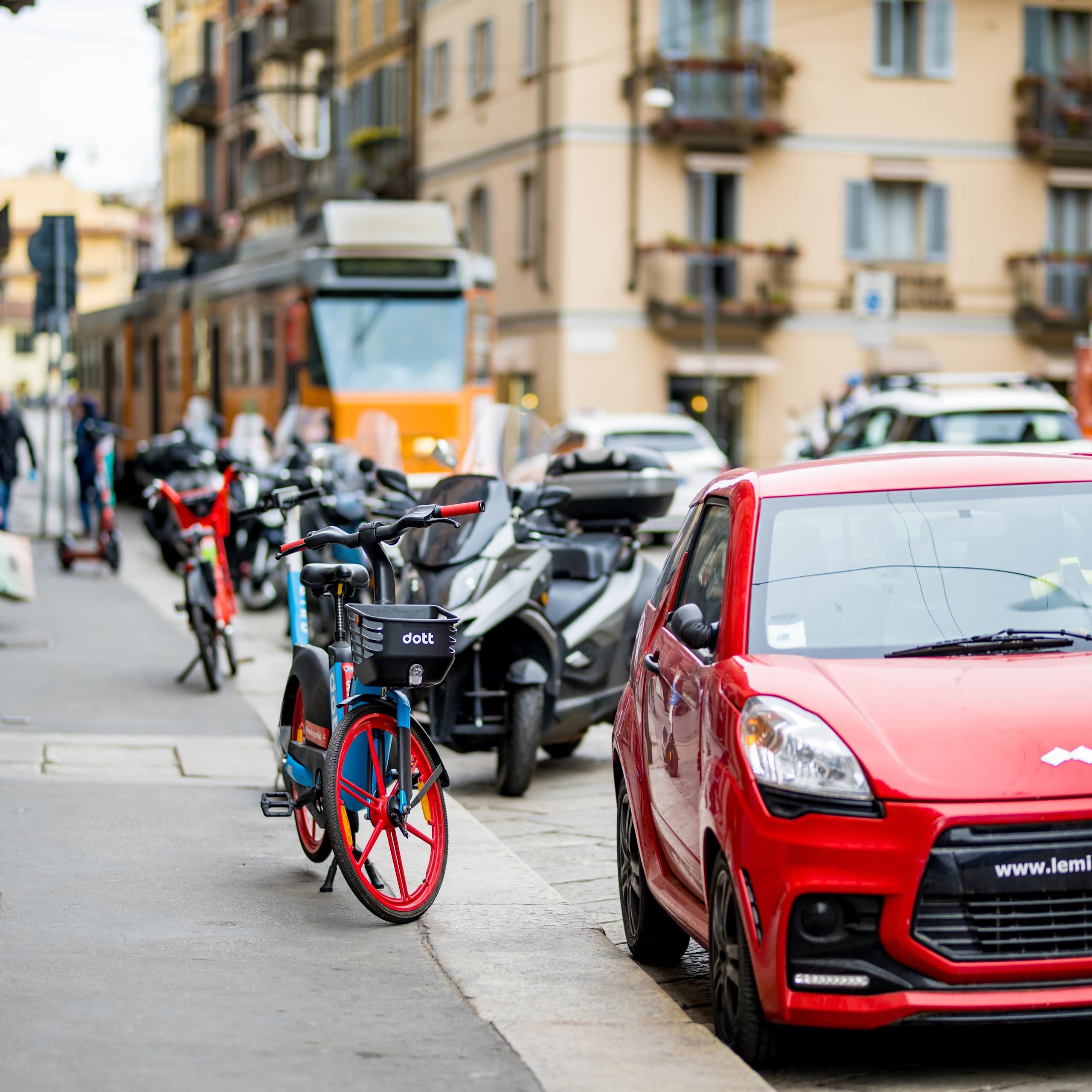 Coches, bicicletas eléctricas y un tranvía en una calle.