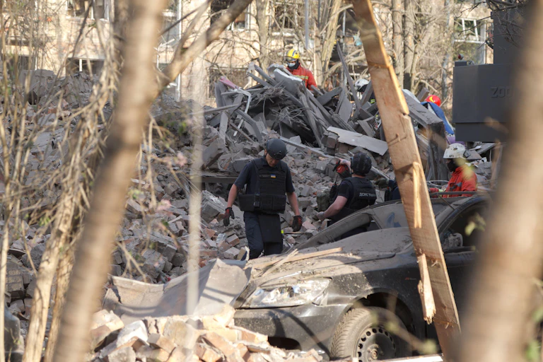 Rescue workers clamber over the wreckage of a Kyiv building hit by a missile attack.