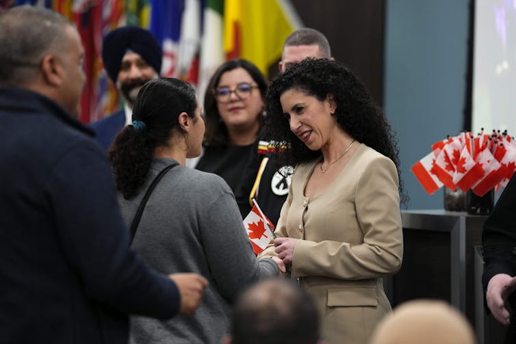 La mujer sonríe en una pareja y se rinde a una pequeña bandera canadiense.