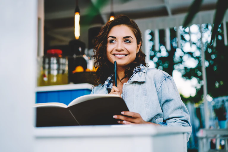 woman sitting with a pen and notebook looking inspired