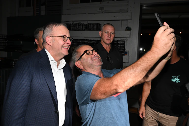 Prime Minister Anthony Albanese smiles as a man takes a selfie.
