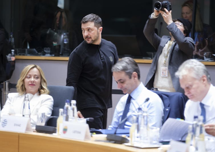 Italy’s Meloni is positioning herself as bridge between EU and Trump – however will it paintings? 1 A man in black walks past a woman and two men seated.