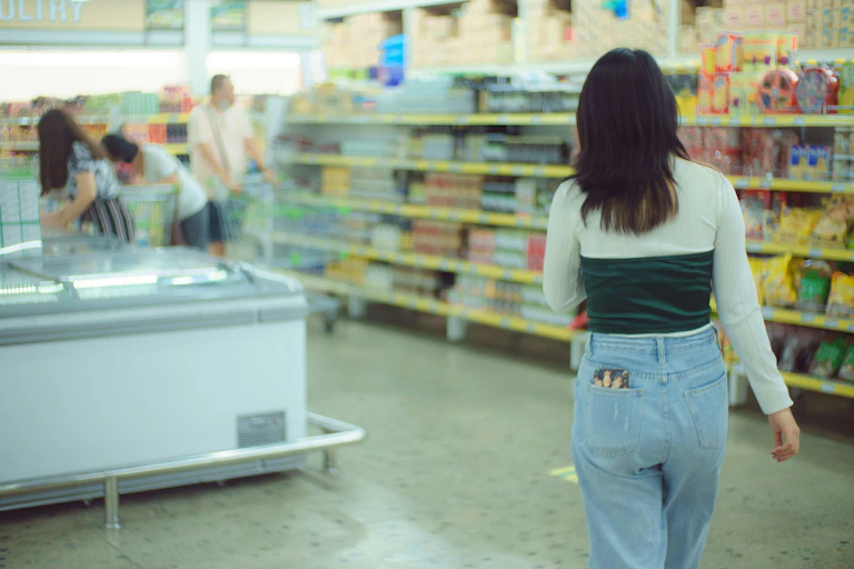 The back of a young woman walking through a grocery store