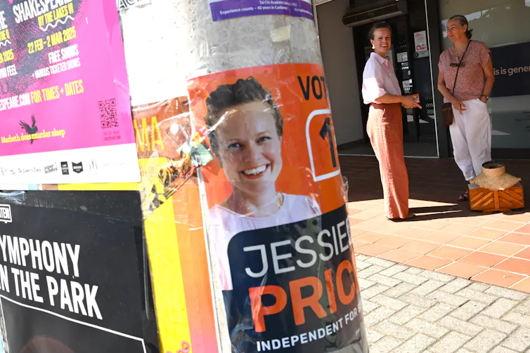 Several campaign posters on a wall on a footpath