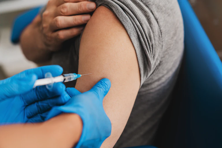 Una aguja se acerca al brazo de alguien.