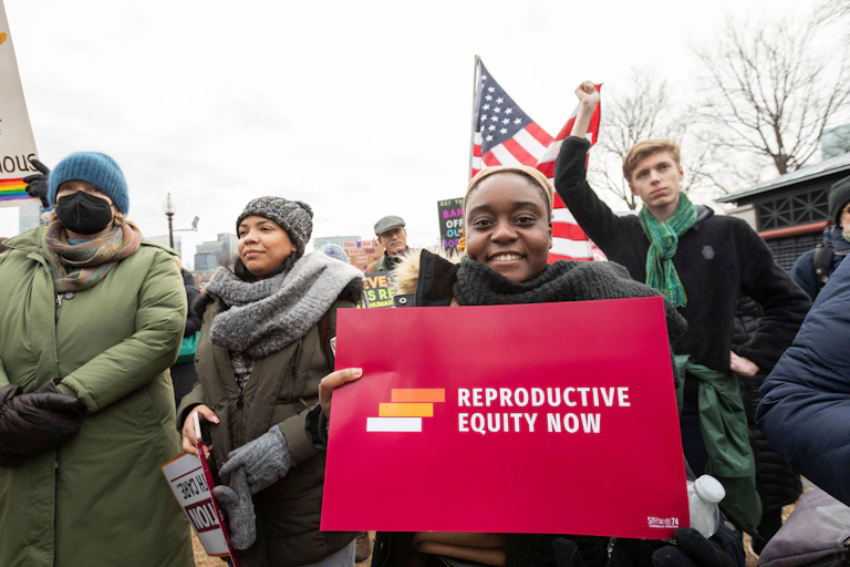 A woman holds up a placard demanding reproductive equity for American women, Boston January 2025.
