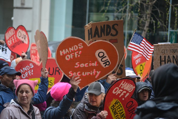 protesters in the us hold signs saying hands off social security