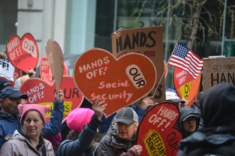 protesters in the us hold signs saying hands off social security