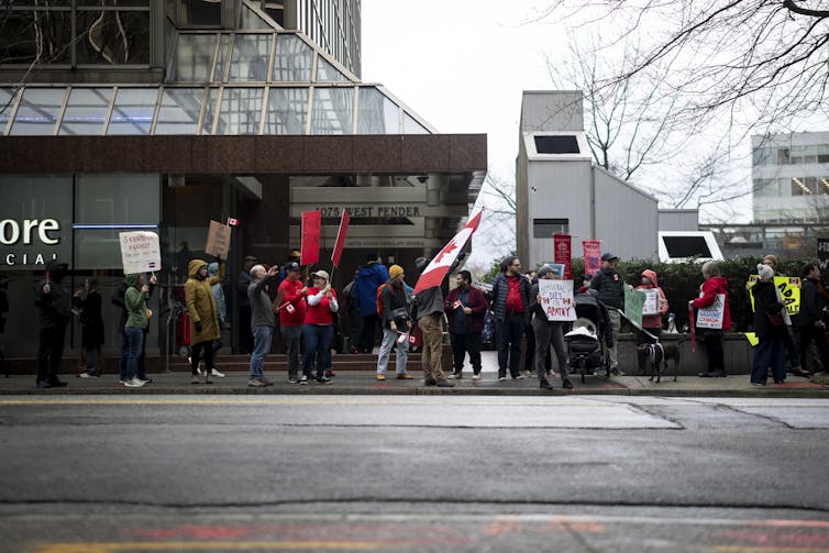 La gente protesta fuera del edificio gris