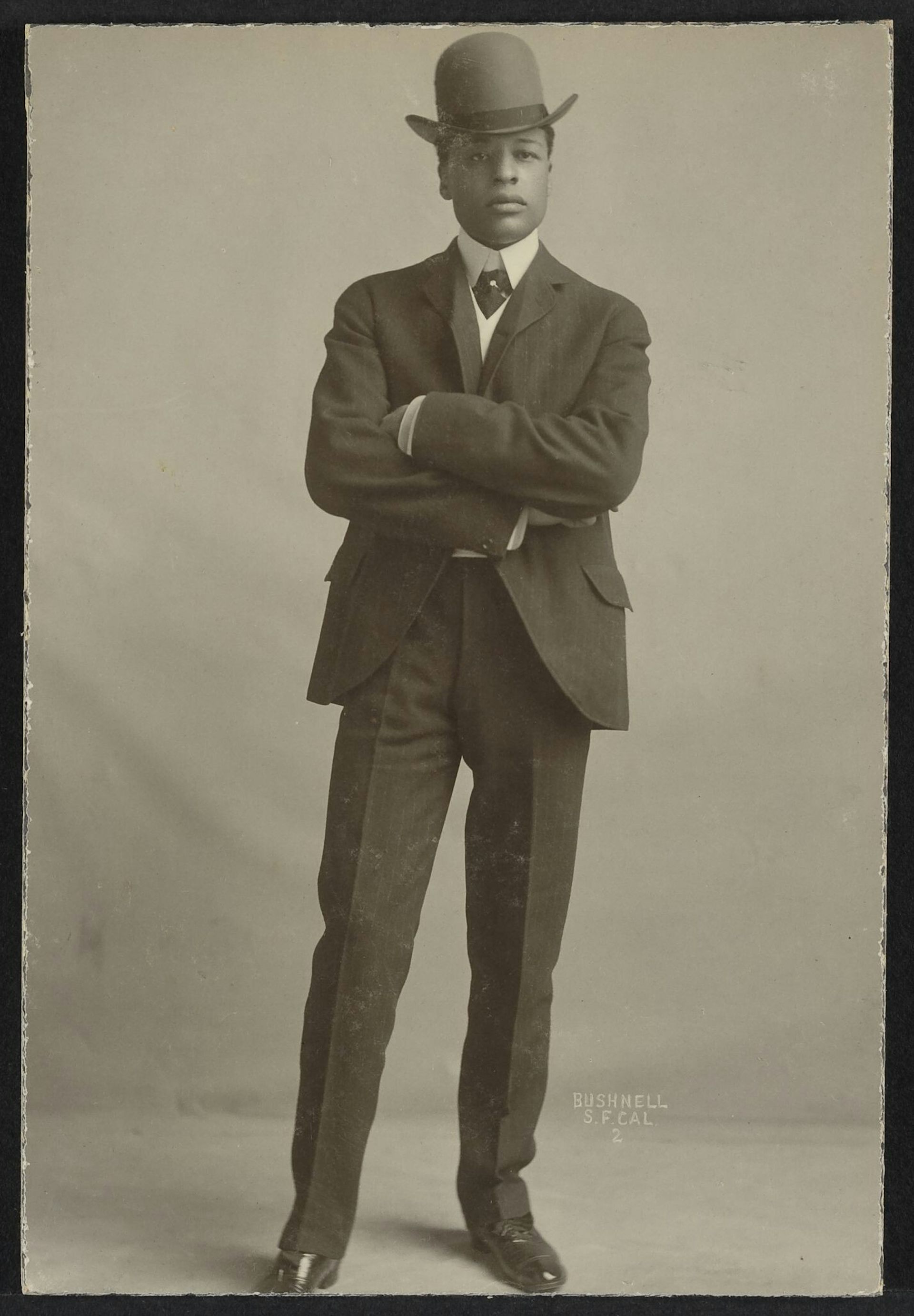 An old black and white photo of a man in a full suit and hat