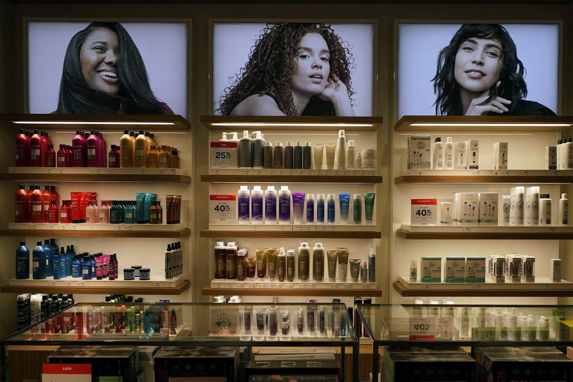 Los productos cosméticos se muestran en almacenes de estantes debajo de tres fotos en mujeres multigraciones