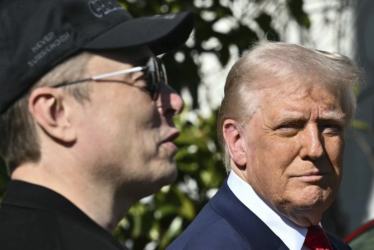 An older white man with pale blonde hair looks at a white man in sunglasses and a ball cap, seen in profile