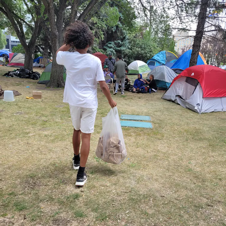 A Black child walking towards tents.